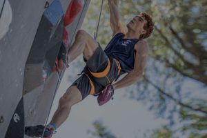 climber using a chalk bag on the side of a wall with a forested background